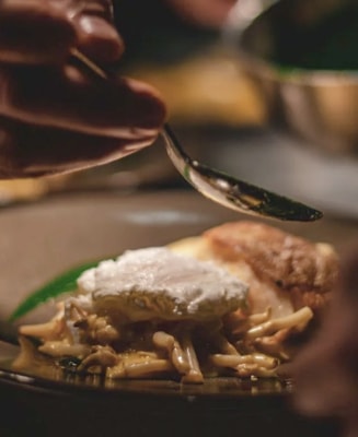 A hand working with a spoon on dish